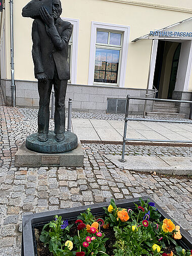 Blumenkasten vorm Rathaus mit der Mattheuer-Statue "Gesichtzeigen" im Hintergrund