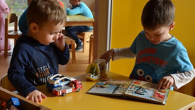 Kinder sitzen am Tisch und spielen miteinander