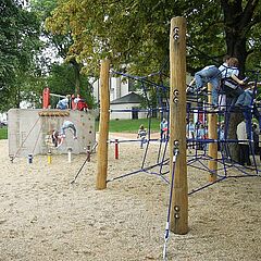 Trinitatispark Spielgeräte Spinndüse und Seilbaum Kletterwand Spinndüse und Spielgerät Seilbaum inmitten eines großen Sandkastens im Trinitatispark